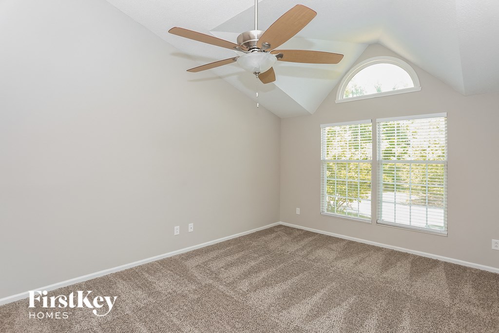 an empty bedroom with a ceiling fan and a window