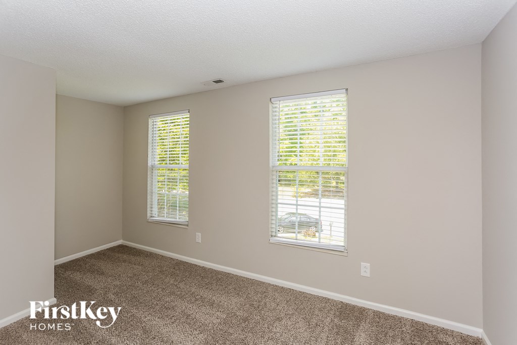a spacious bedroom with two windows and a carpeted floor