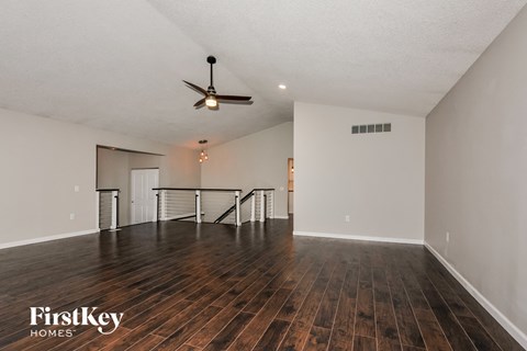 A spacious room with wooden floors and a ceiling fan.