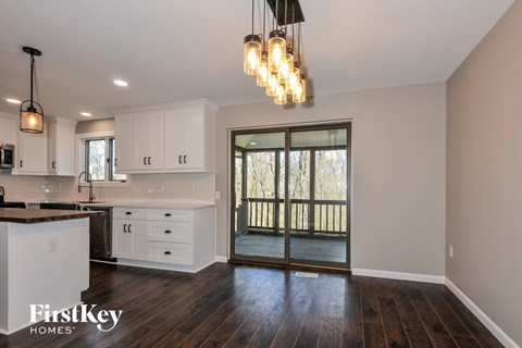 A kitchen with a white counter top and wooden floors.
