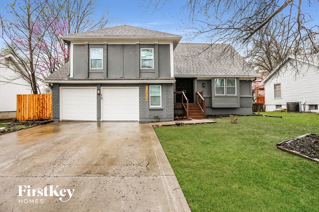 A grey house with a brown fence and a white garage door.