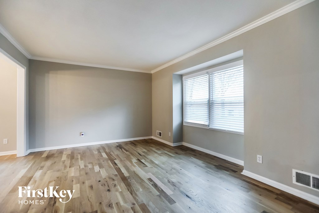 A room with wooden flooring and a window with blinds.