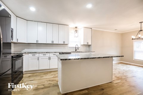 A kitchen with white cabinets and a marble countertop.