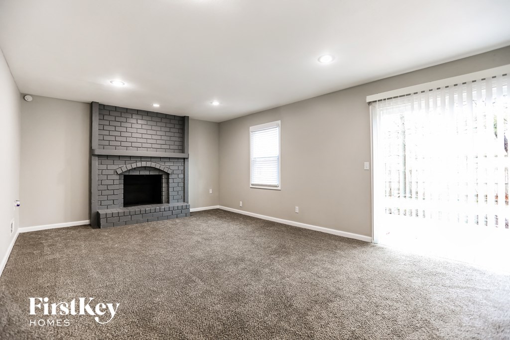 A spacious living room with a fireplace and a carpeted floor.