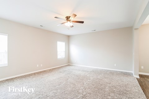 a spacious living room with a ceiling fan and carpet