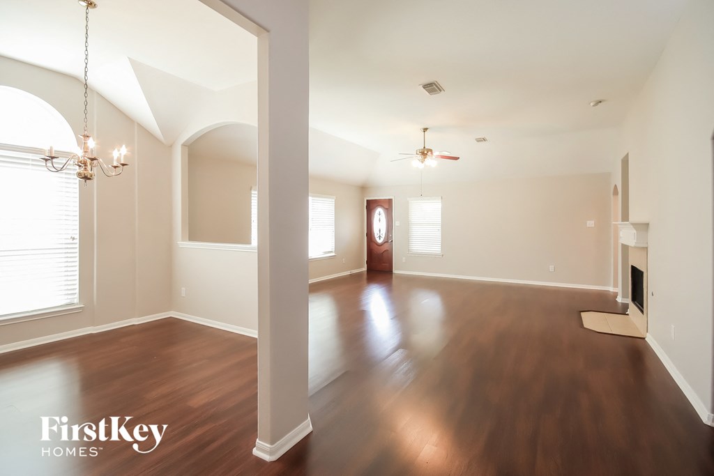 an empty living room with hardwood flooring and white walls