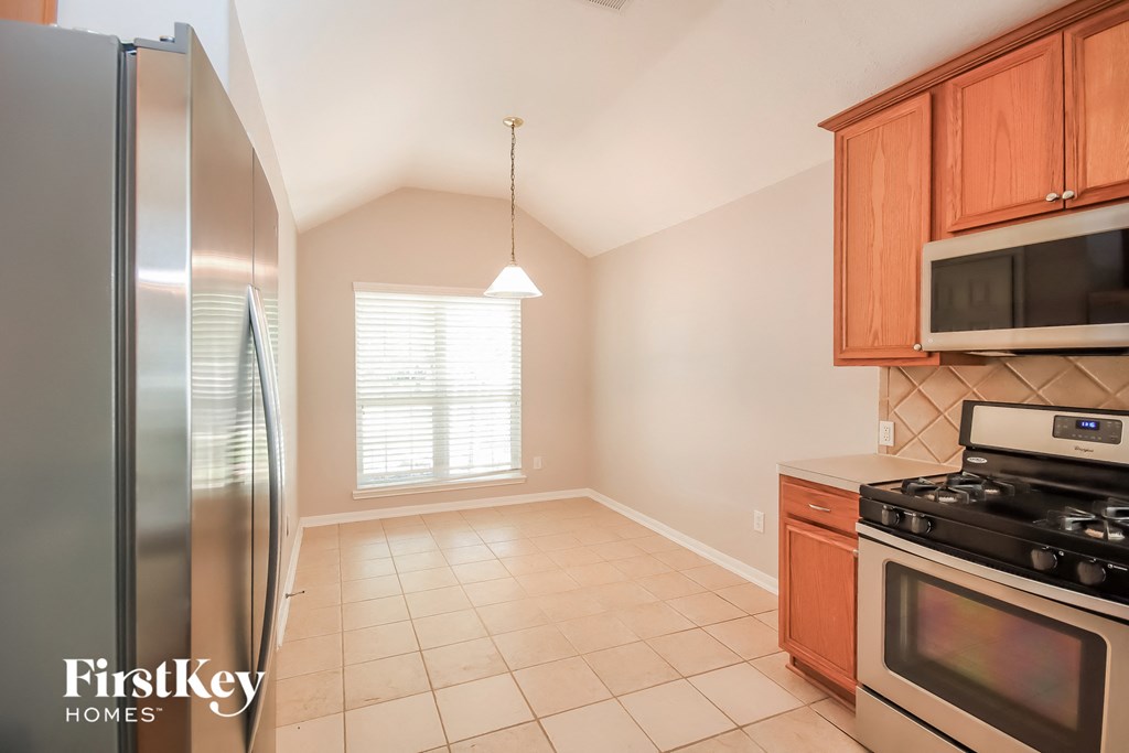 an empty kitchen with stainless steel appliances and wooden cabinets