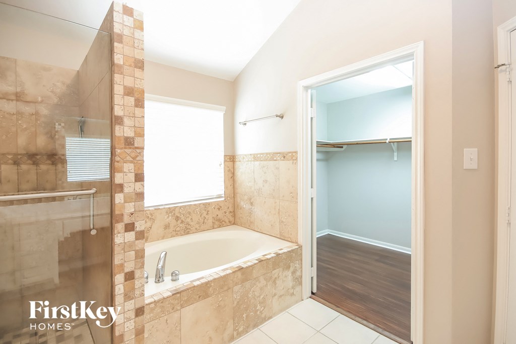 a bathroom with a tub and a shower and a closet