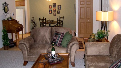 a living room with a couch and a table with a bottle of wine