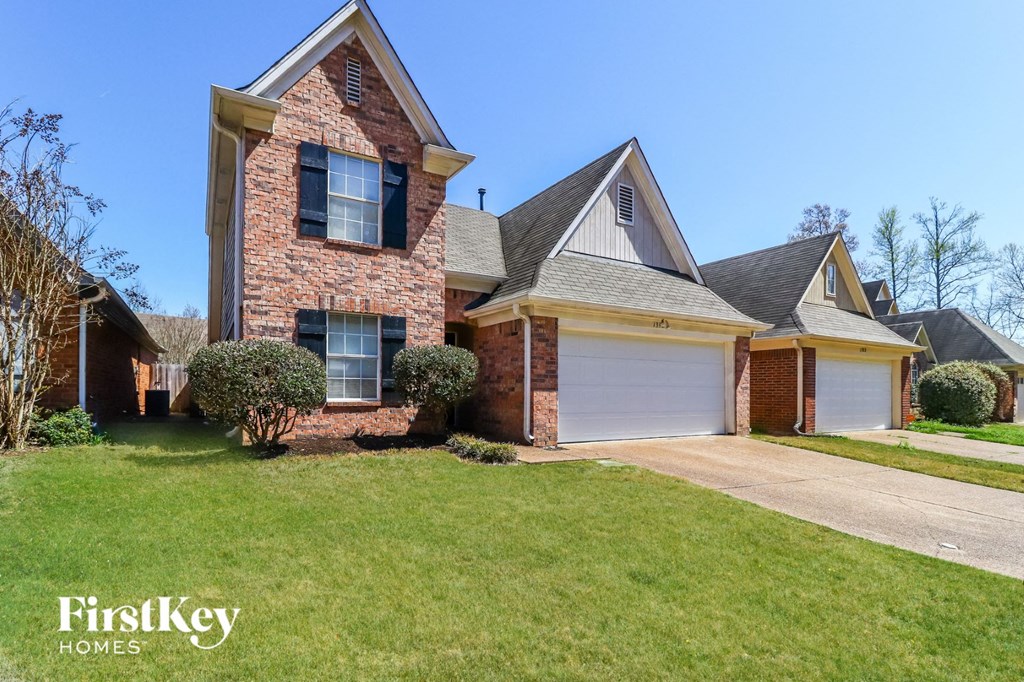 a brick house with a white garage door and a lawn