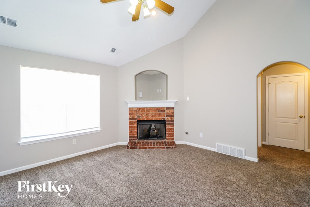 a living room with a brick fireplace and a ceiling fan