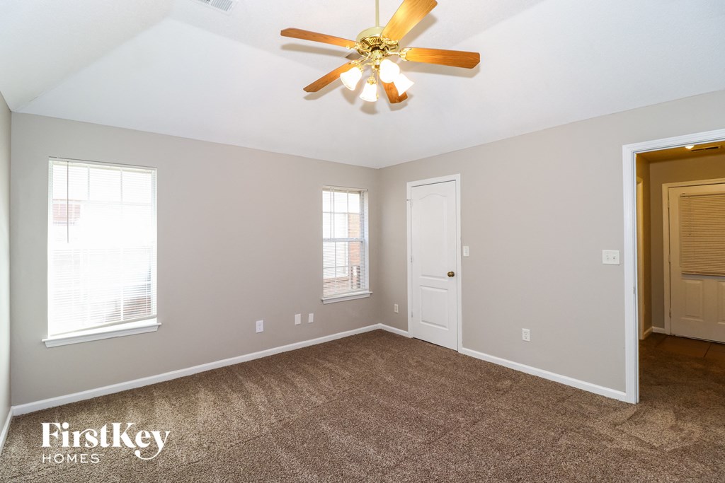 the master bedroom has a ceiling fan and a carpeted floor
