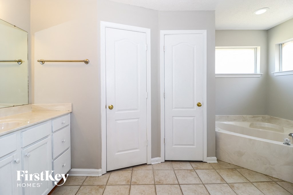 a bathroom with two white doors and a tub and a sink