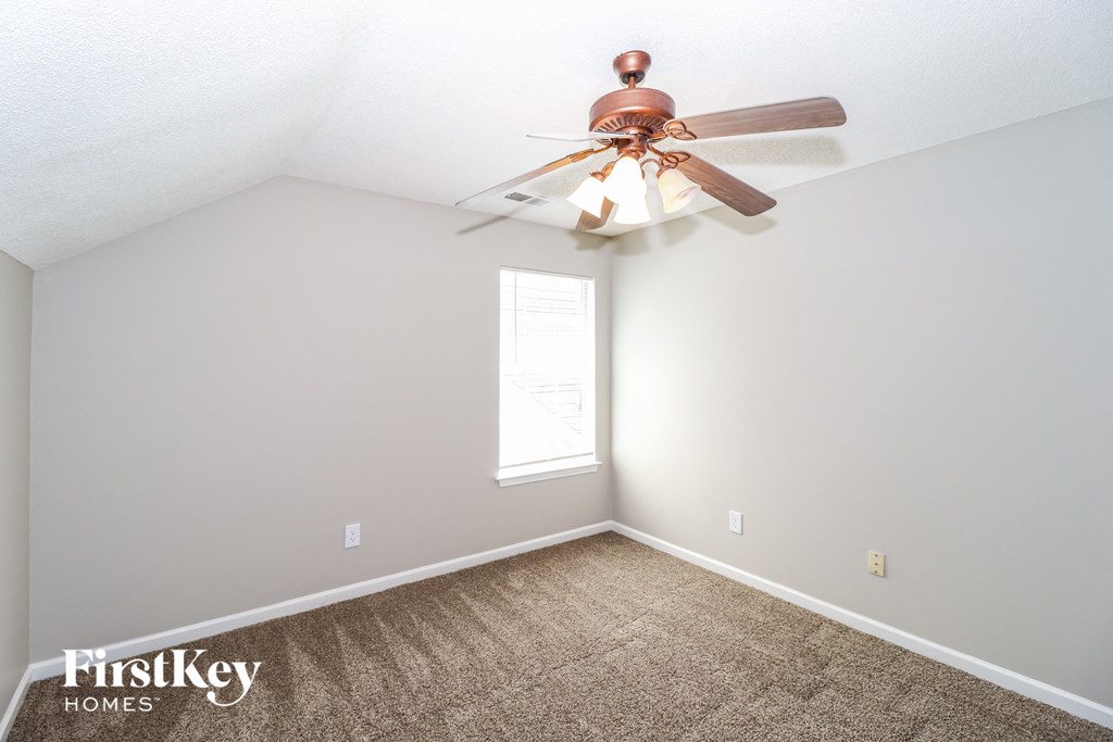 a bedroom with a ceiling fan and a carpet