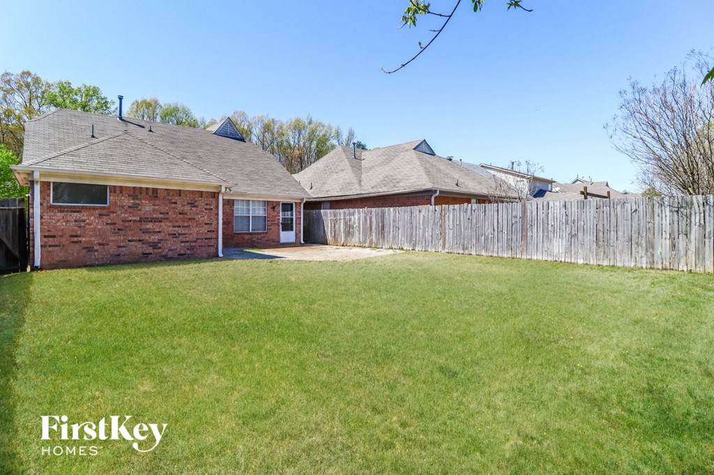 a backyard with a brick house and a wooden fence