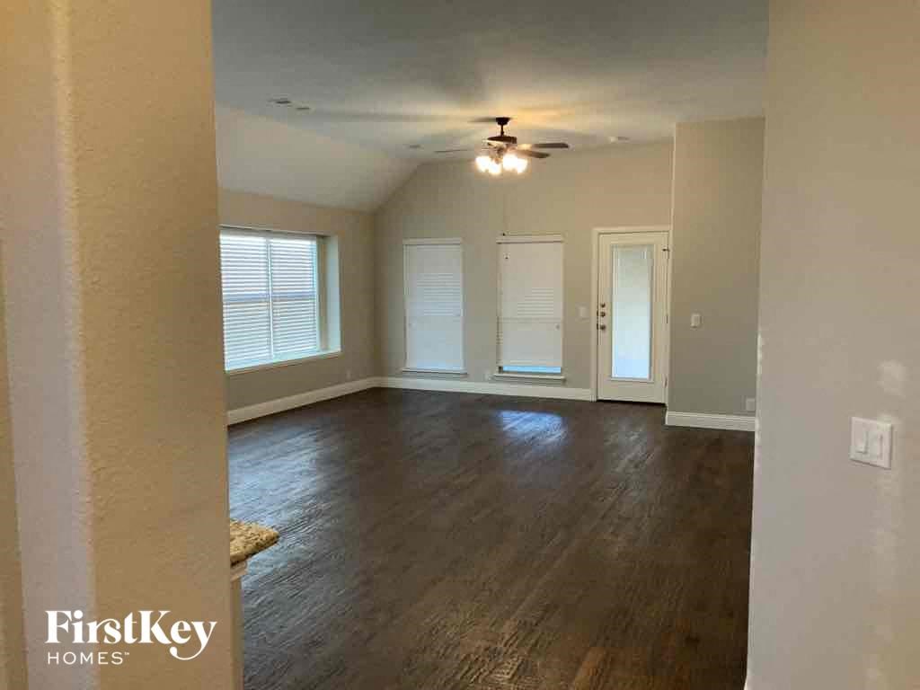 an empty living room with wood floors and a ceiling fan