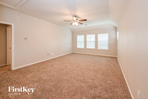 a spacious living room with carpet and a ceiling fan