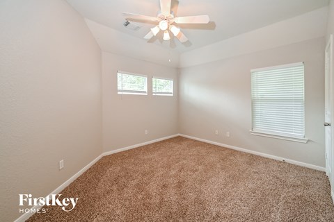 the master bedroom has a ceiling fan and beige carpet