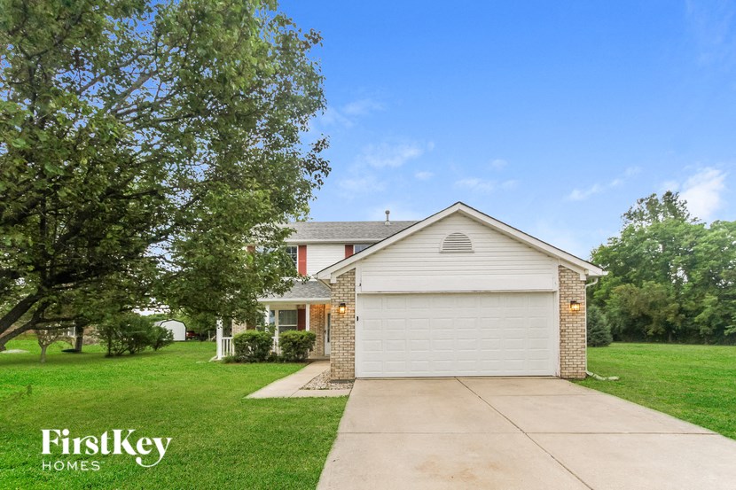 a white house with a driveway and a lawn