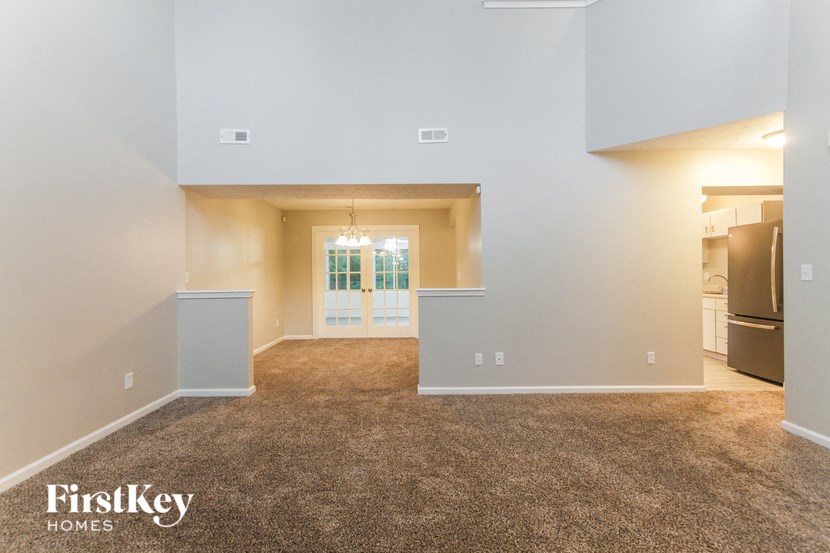 a living room with a carpeted floor and a door to a kitchen