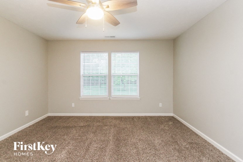 an empty room with a ceiling fan and a window