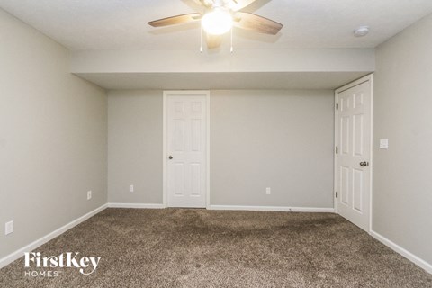 the living room of a home with carpet and a ceiling fan