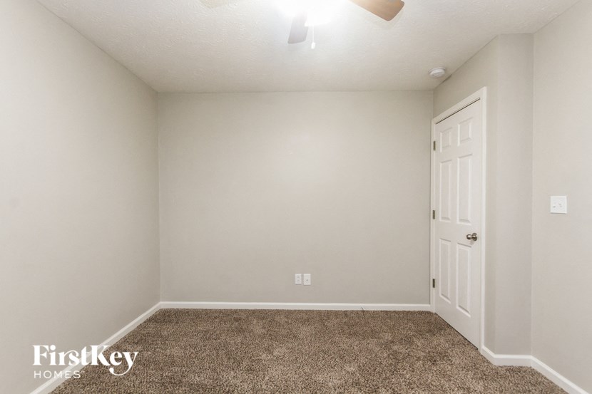 a bedroom with a white door and a carpeted floor