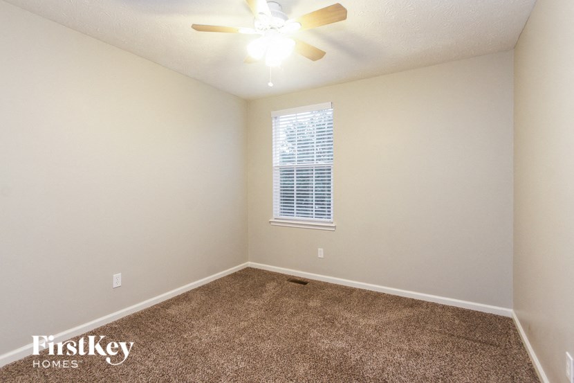 an empty room with a ceiling fan and a window