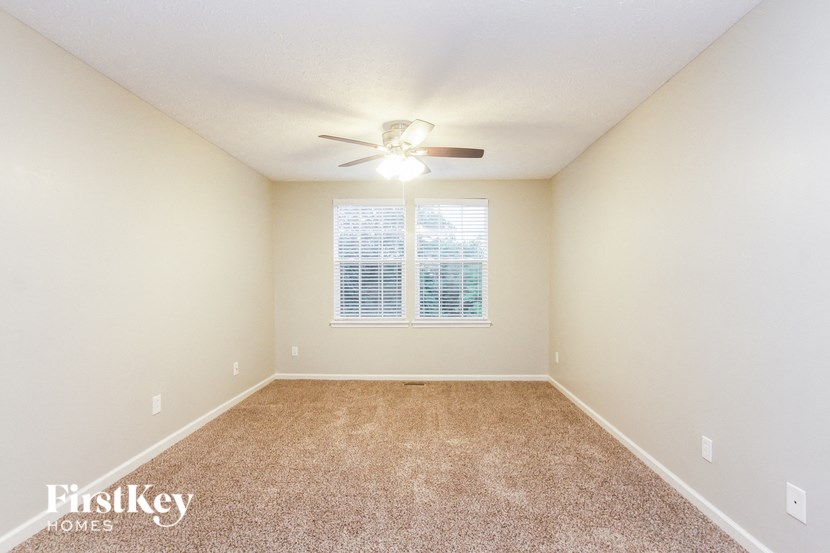 an empty living room with a ceiling fan and a window