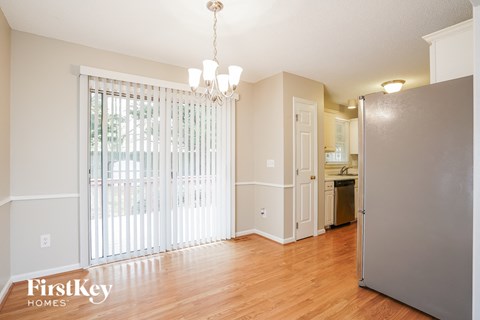 A kitchen area with a refrigerator, a chandelier, and a dining area with a table and chairs.