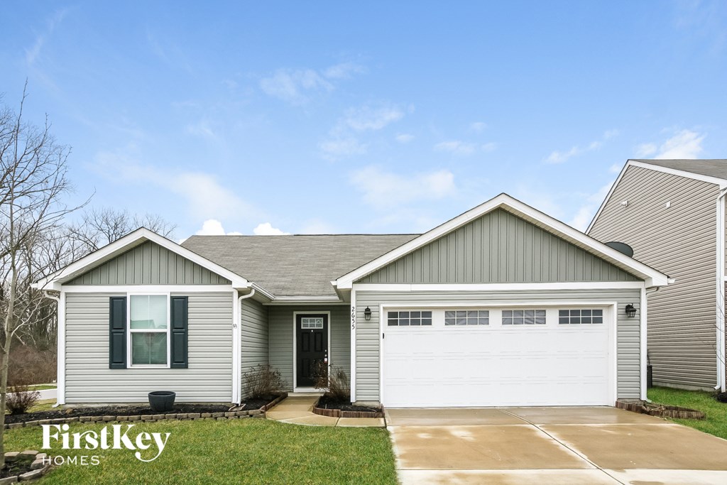 A grey house with a white garage door and a black door.