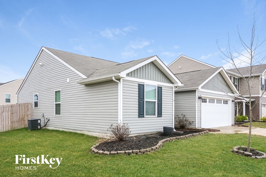 A house with a grey siding and a white garage door is shown.