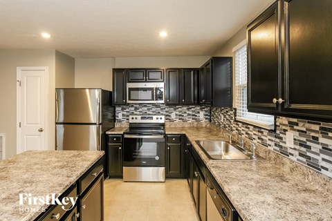 A kitchen with black cabinets and a stainless steel refrigerator.