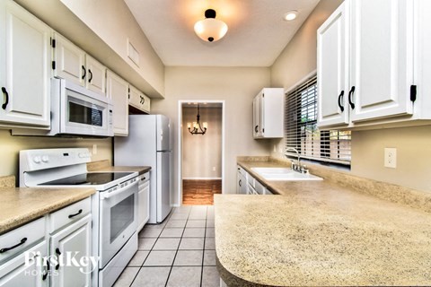 a kitchen with white cabinets and white appliances and counter tops