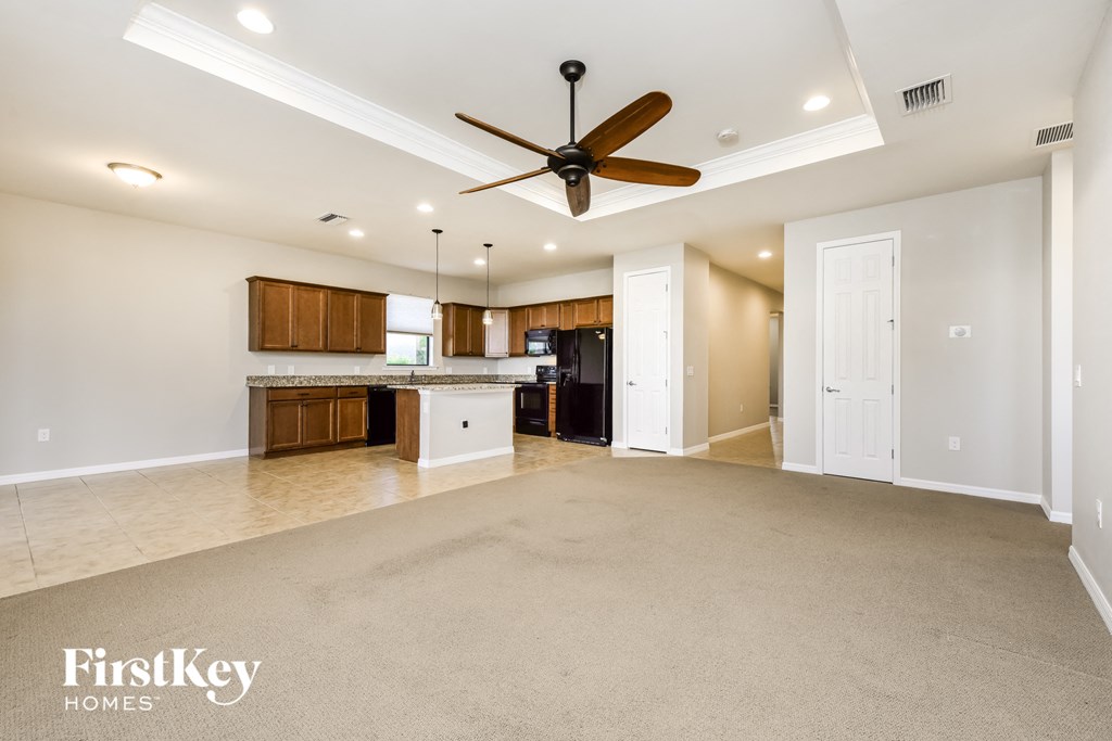 an empty living room and kitchen with a ceiling fan