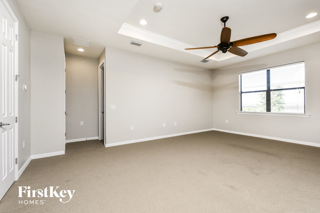 an empty living room with a ceiling fan and a window
