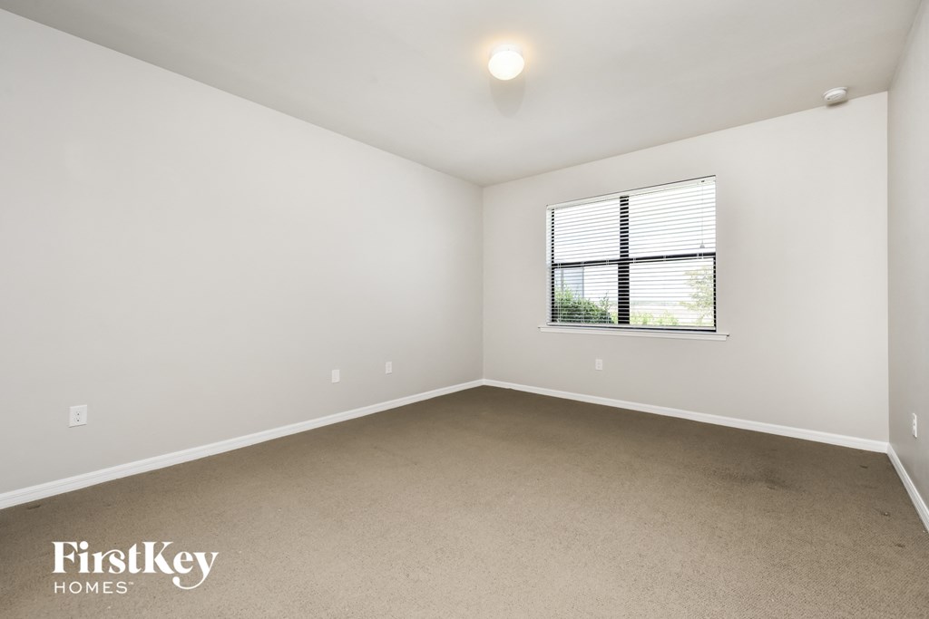 a bedroom with white walls and carpet and a window