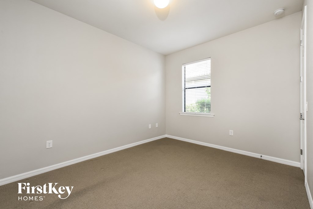 a bedroom with white walls and carpet and a window