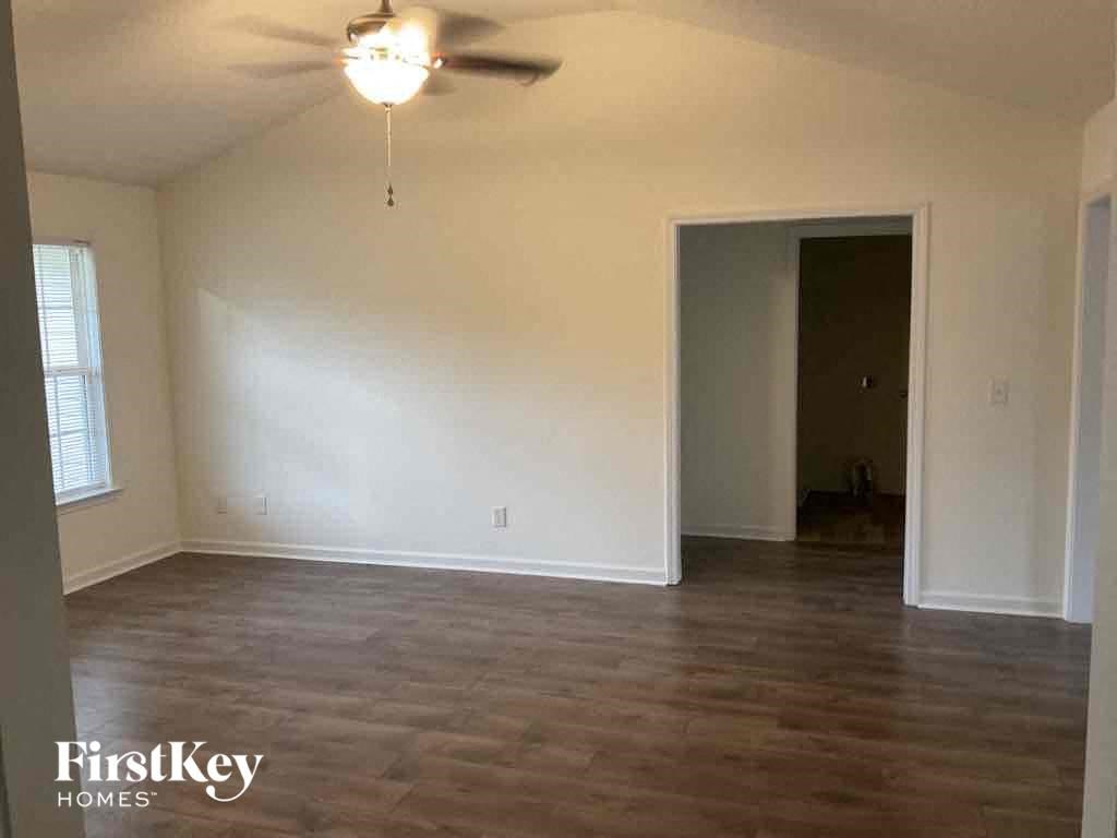 A room with a ceiling fan and wooden flooring.