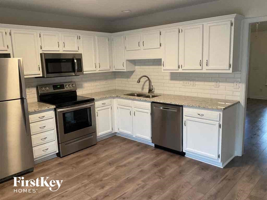 A kitchen with white cabinets and a wooden floor.