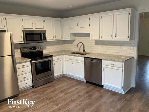 A kitchen with white cabinets and a wooden floor.