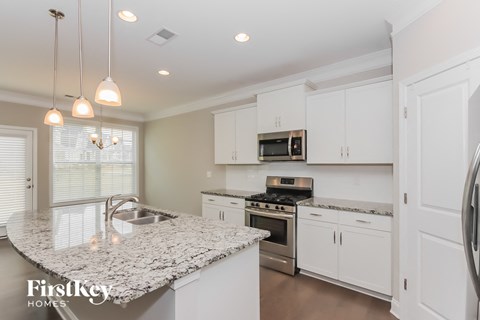 a white kitchen with granite counter tops and stainless steel appliances