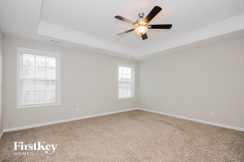 the master bedroom has a ceiling fan and beige carpet
