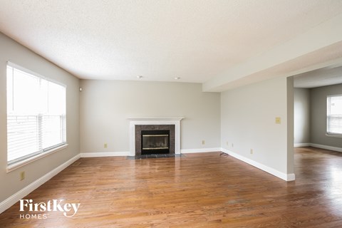 A spacious room with a fireplace and wooden floors.