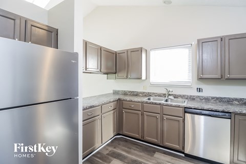 A kitchen with a stainless steel refrigerator and brown cabinets.
