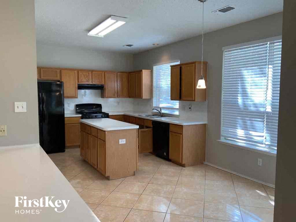 an empty kitchen with wooden cabinets and a black refrigerator