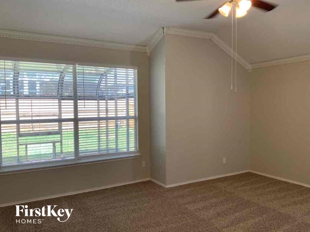an empty living room with a window and a ceiling fan