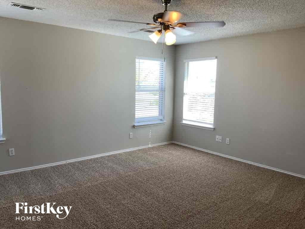 an empty living room with a ceiling fan and two windows