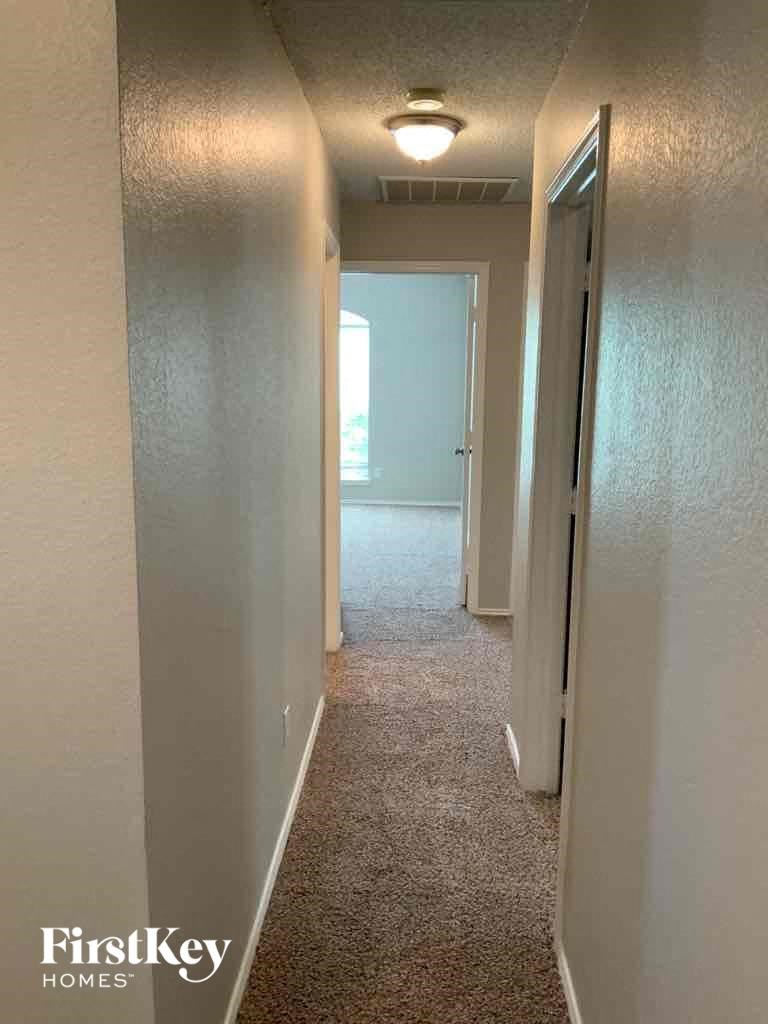 a hallway with an open door and a hallway view of a room with a closet