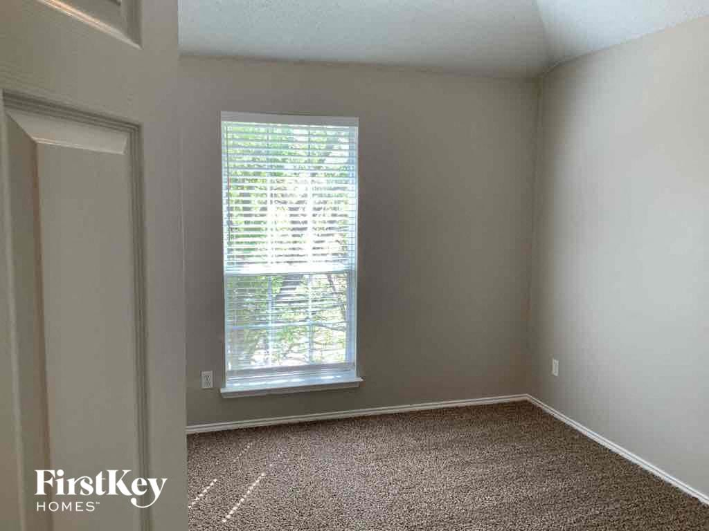 an empty bedroom with a window and a carpeted floor